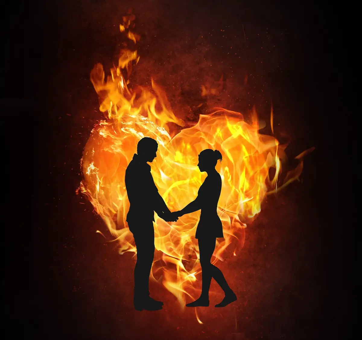 Pareja tomada de la mano frente a un corazón de fuego: amarres de amor